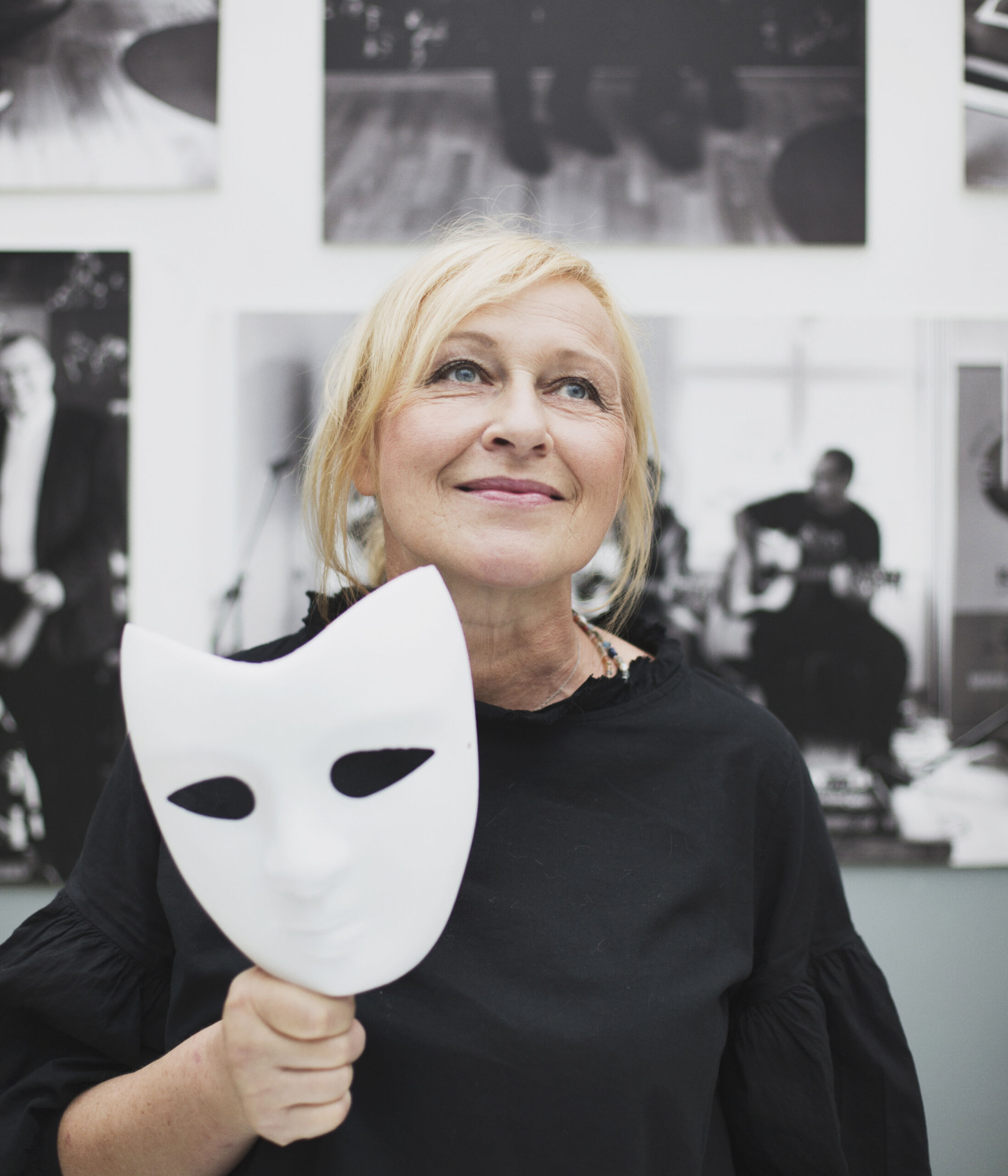 Kobieta trzyma w dłoni białą maskę teatralną